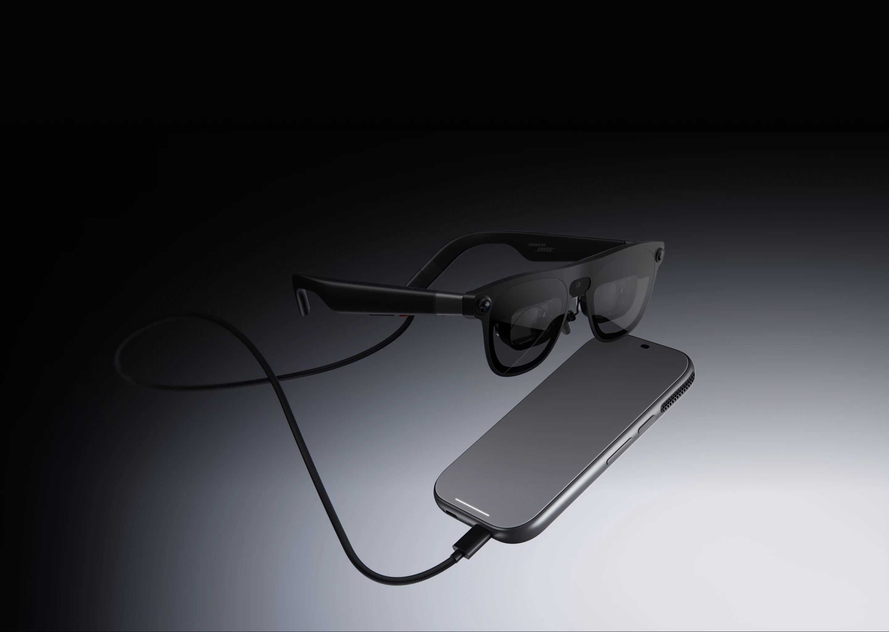 XREAL AURA glasses connected by a braided USB-C cable to the compute puck, lying on a dark gradient background