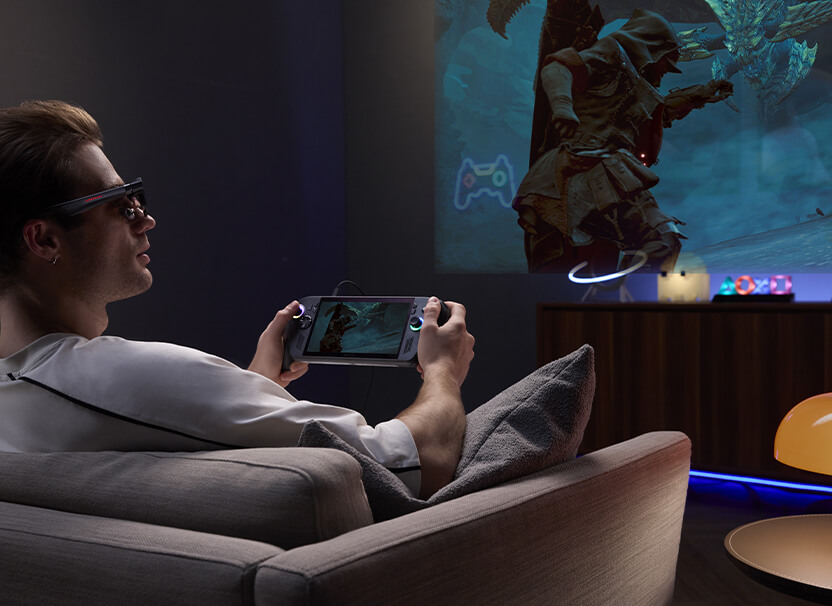 A Man using ROG R1 Gaming AR glasses to play Monster Hunter game on controllers with PC set-up at his gaming station